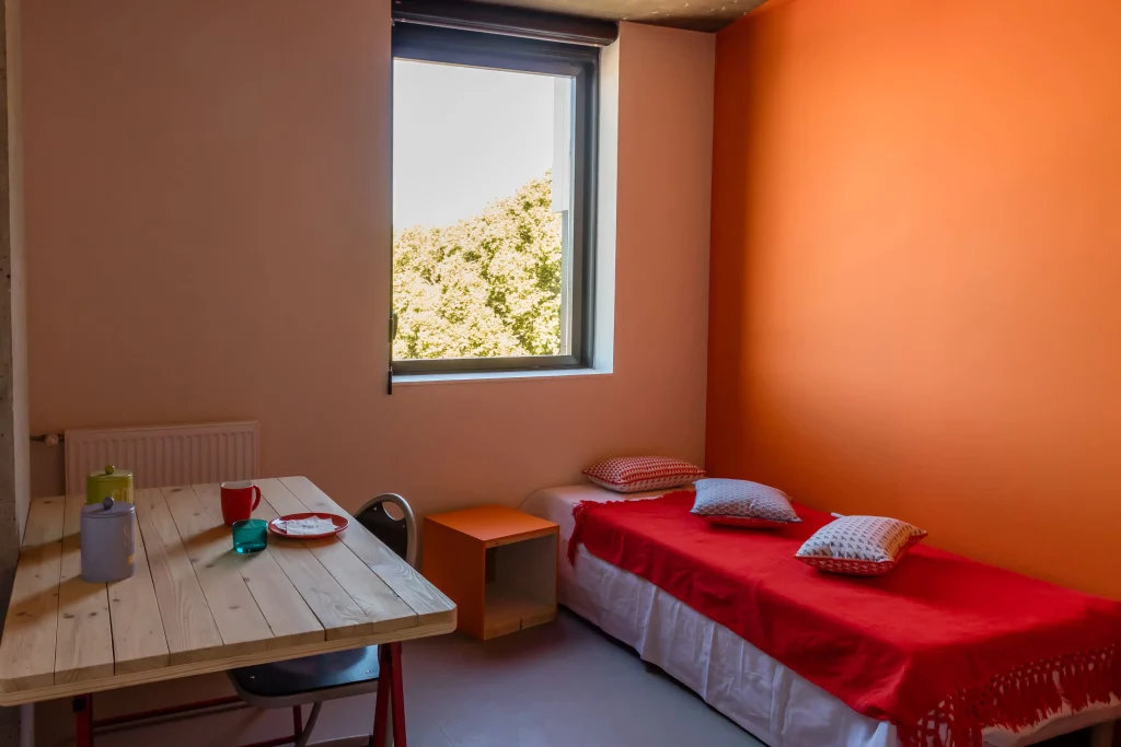 Studio étudiant équipé avec un bureau en bois en seconde vie et un lit une place confortable.