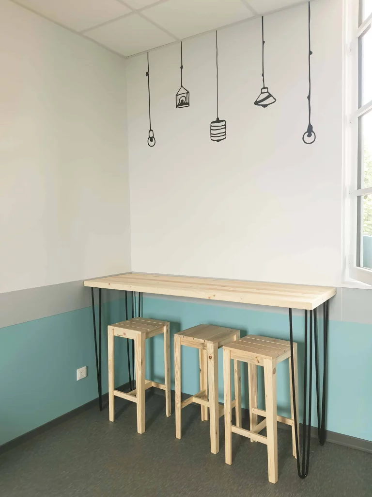 Tabourets en bois et table en bois sous un stickers de multiples ampoules.