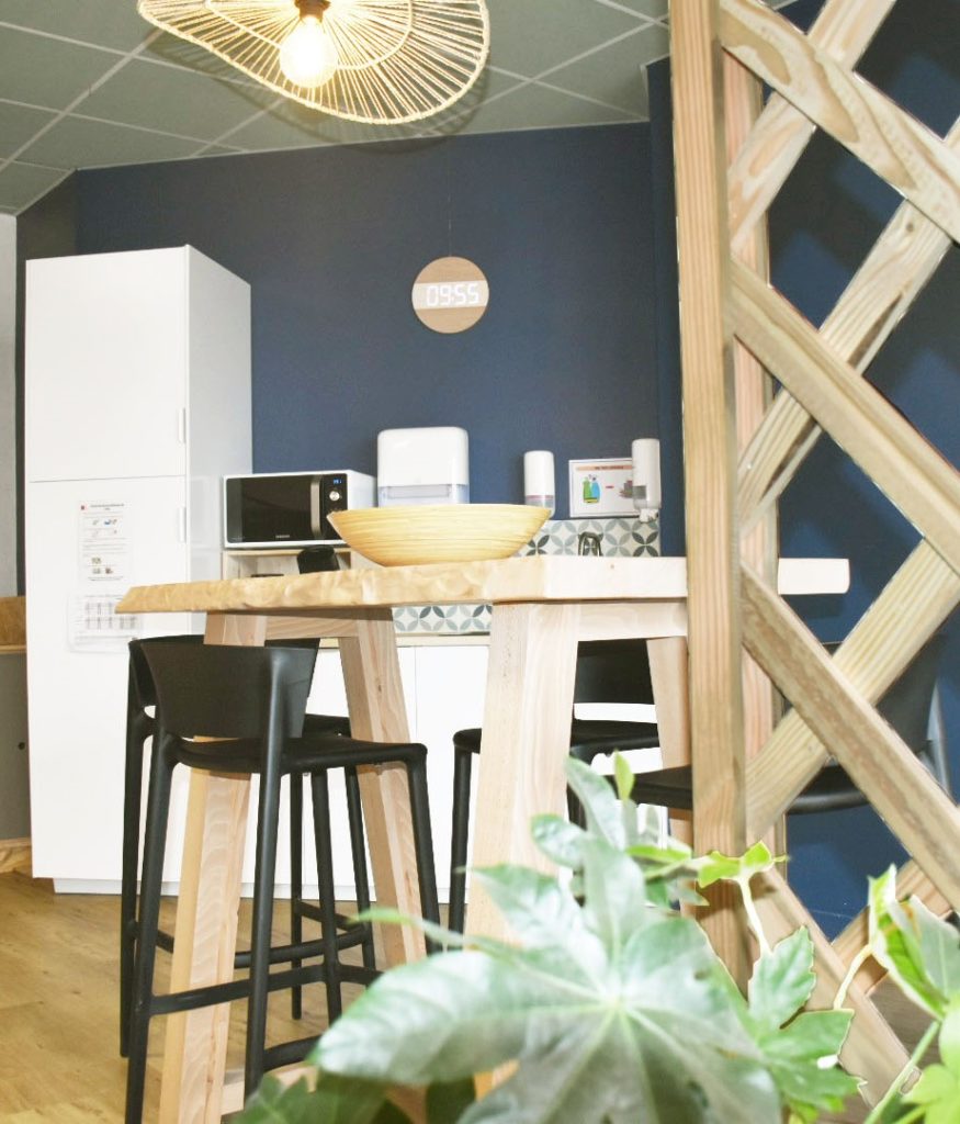 Au premier plan, une jardinière avec de jolies plantes et derrière un espace aménagé pour se reposer, le tout étant fabriqué soit par les apprentis soit récupéré de manière responsable.