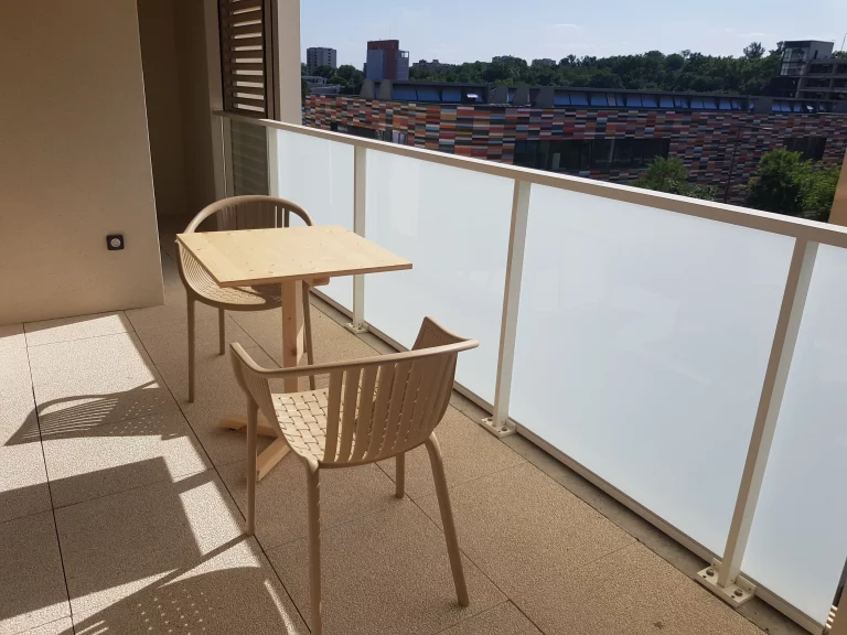 Vue d'un balcon fermé paisible équipé par du mobilier de réemploi esthétique et moderne.